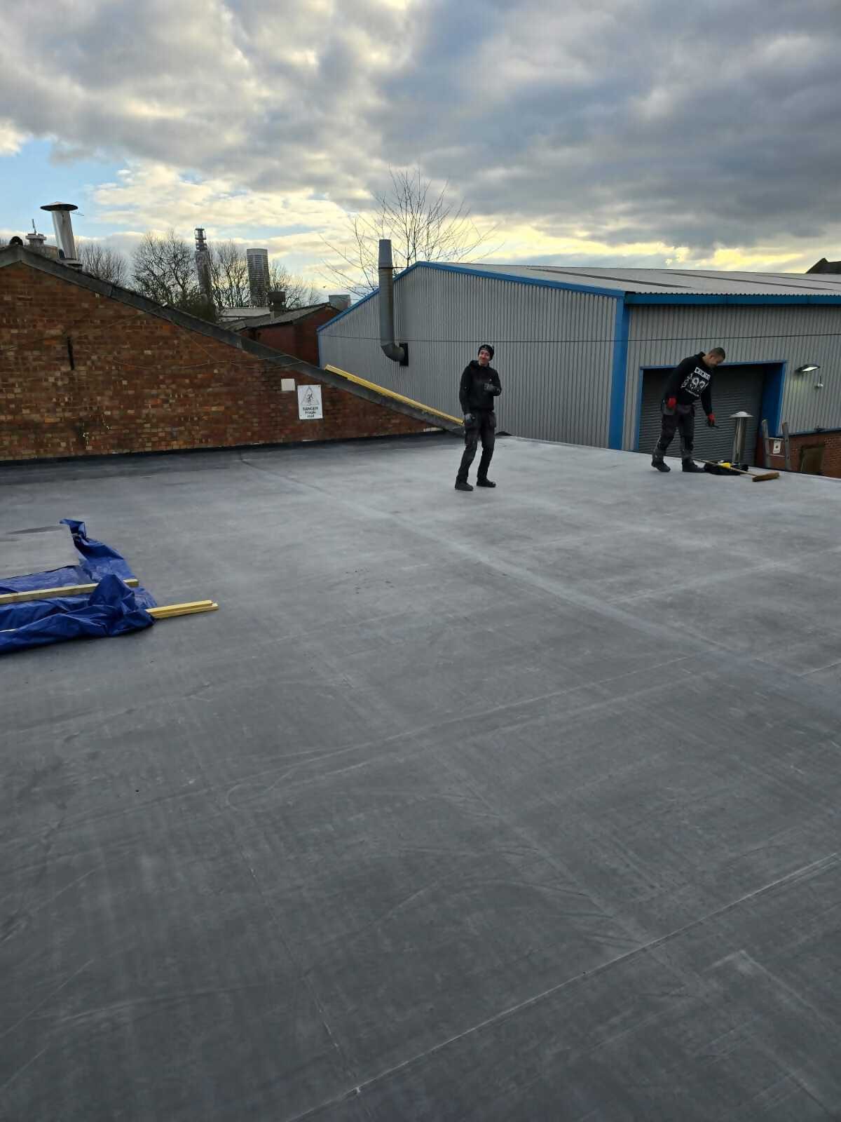 Roofer installing a grey flat roofing system