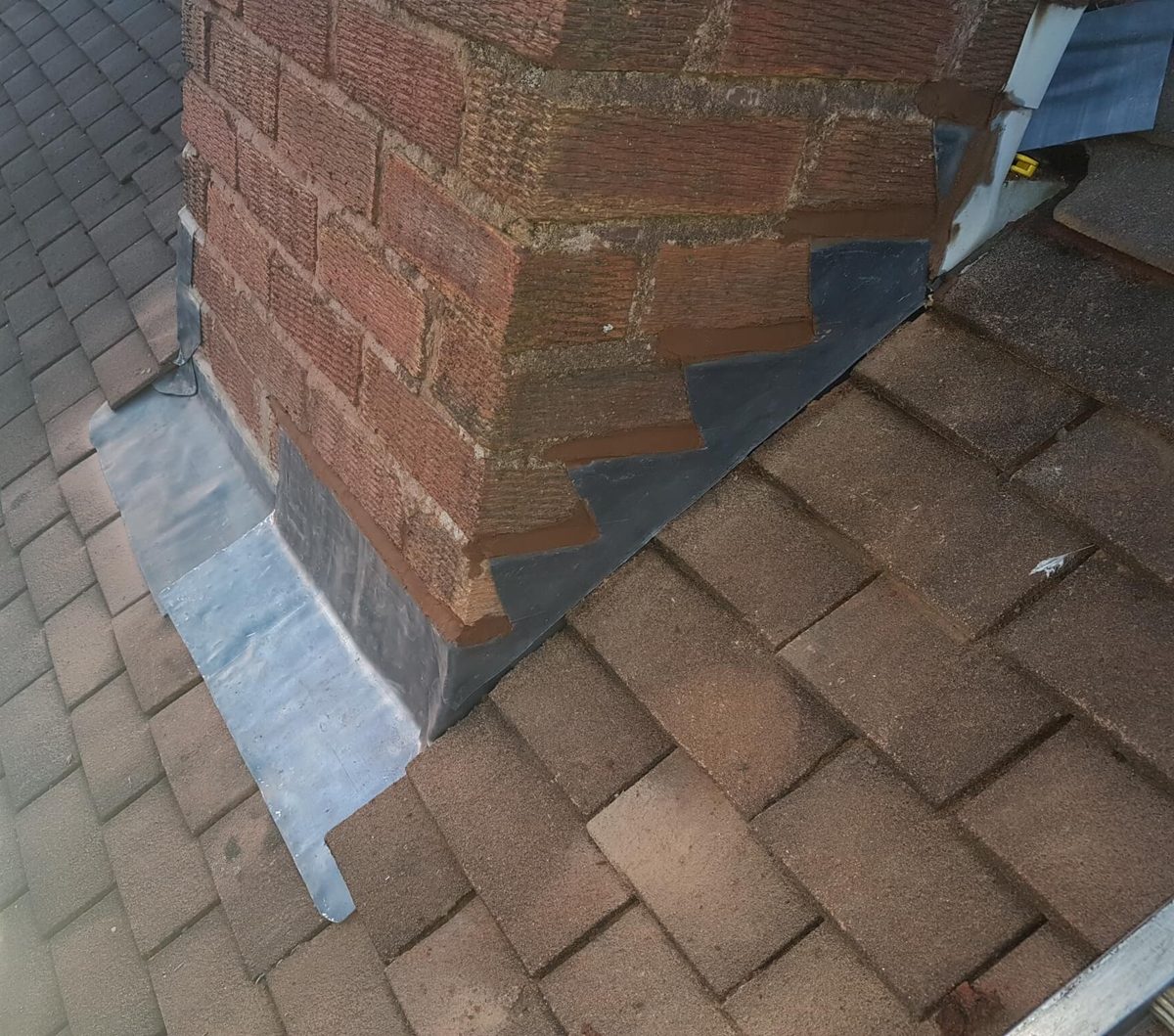 New lead flashing installed beside roof tiles and brickwork